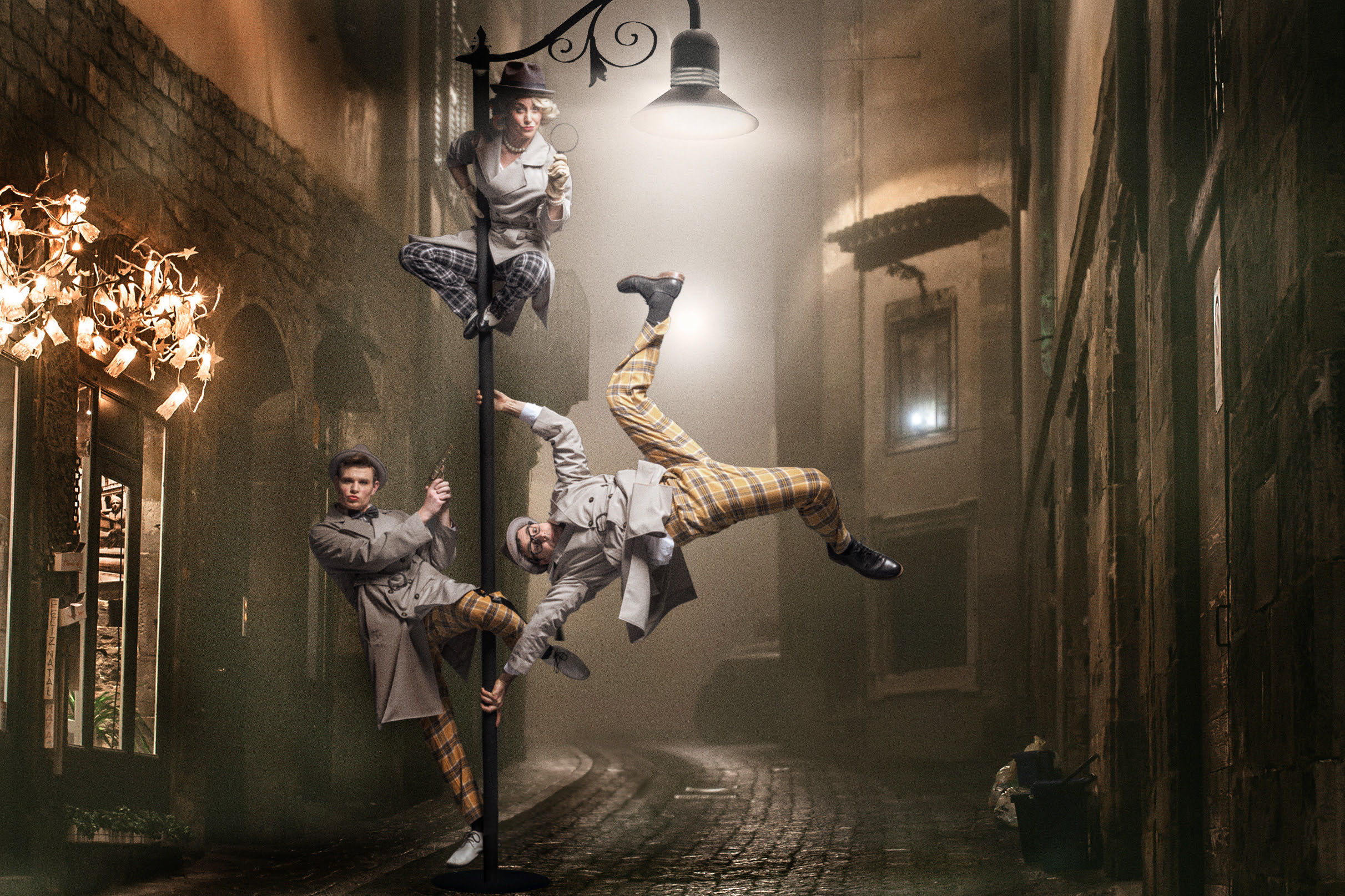 Dumtectives in Cirque Noir acrobats in detective outfits post on a street light